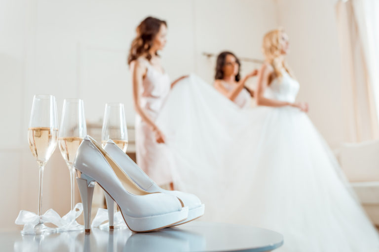 Focus image of a heels and wine glass over a blur image of a bride